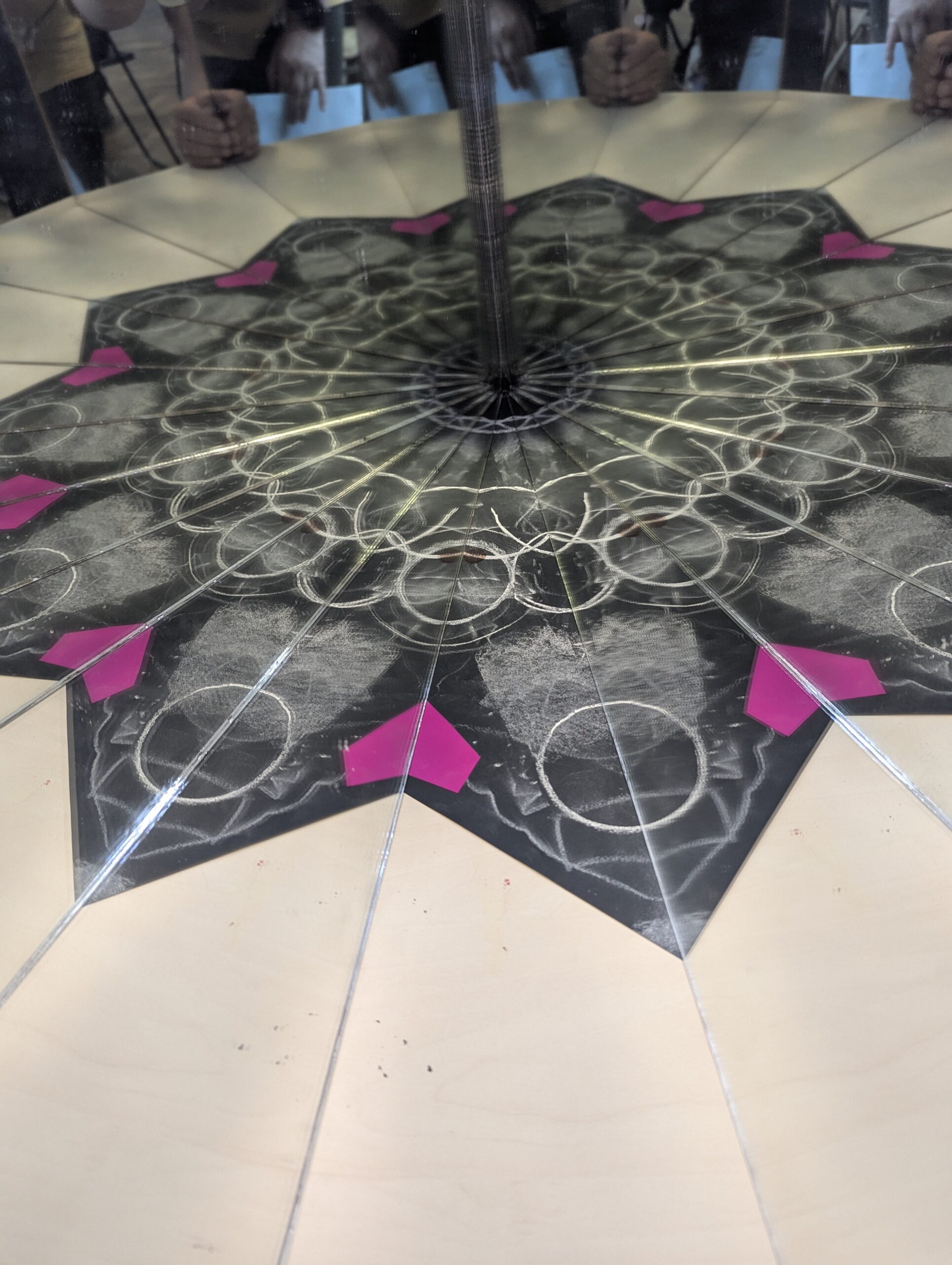 Two mirrors creating a black-and-pink kaleidoscope-like star pattern from a hand-drawn design
